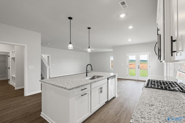 kitchen with a kitchen island with sink, stainless steel appliances, light stone countertops, sink, and white cabinetry