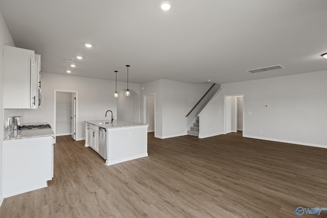 kitchen featuring a kitchen island with sink, light wood-type flooring, sink, white cabinetry, and decorative light fixtures