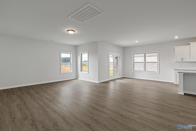 unfurnished living room with a healthy amount of sunlight and dark hardwood / wood-style floors