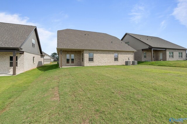 back of property with central AC unit and a lawn