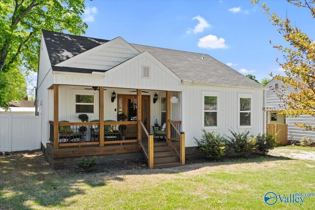 back of house with roof with shingles, fence, a lawn, and a ceiling fan