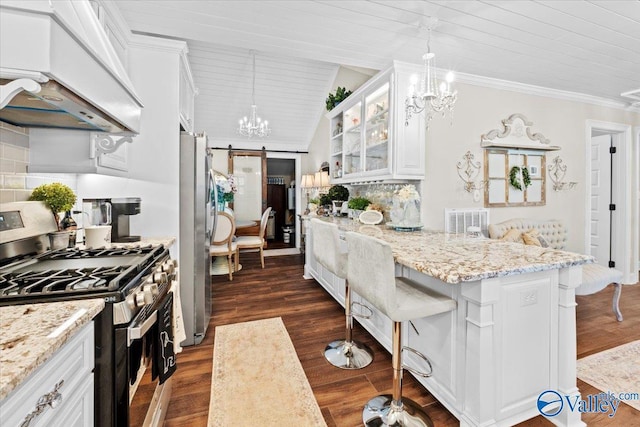 kitchen with custom exhaust hood, a breakfast bar, a chandelier, a barn door, and stainless steel appliances