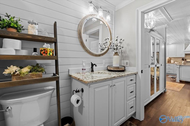 bathroom featuring tasteful backsplash, ornamental molding, toilet, vanity, and wood finished floors