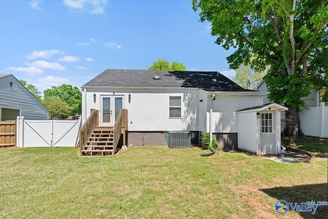 rear view of house with an outdoor structure, a fenced backyard, a gate, a lawn, and a storage unit
