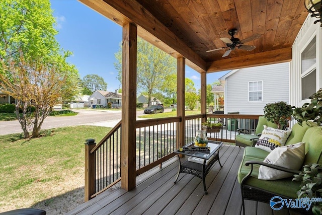 wooden deck with a residential view, ceiling fan, covered porch, and a lawn
