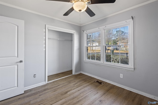 unfurnished bedroom with ceiling fan, a closet, crown molding, and wood-type flooring