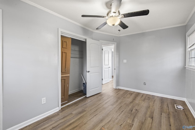 unfurnished bedroom with ceiling fan, a closet, crown molding, and light wood-type flooring