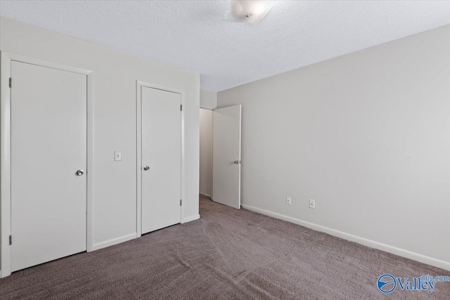 unfurnished bedroom with dark colored carpet and a textured ceiling