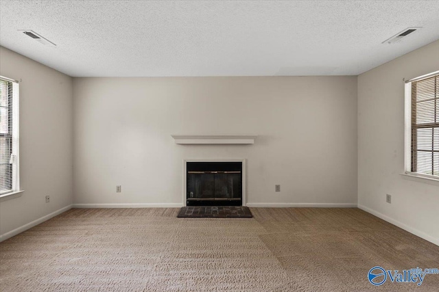 unfurnished living room with carpet floors, a brick fireplace, and a textured ceiling