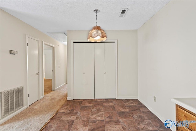 unfurnished bedroom featuring a textured ceiling, a closet, and dark colored carpet