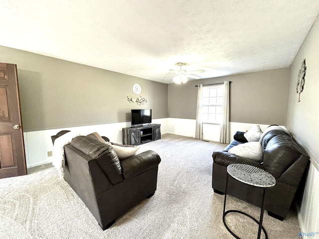 living area with a textured ceiling, a ceiling fan, and carpet