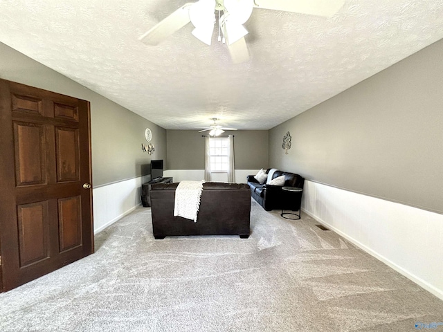 carpeted living room with a textured ceiling and ceiling fan