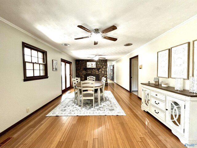 dining space featuring crown molding, a ceiling fan, wood finished floors, a textured ceiling, and baseboards