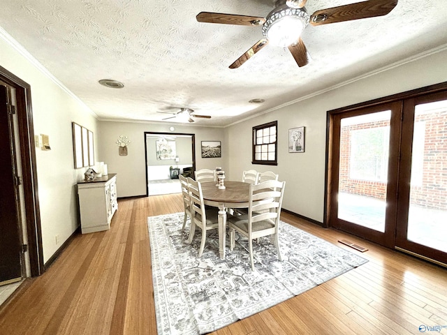 dining space with a ceiling fan, crown molding, a textured ceiling, and light wood-type flooring
