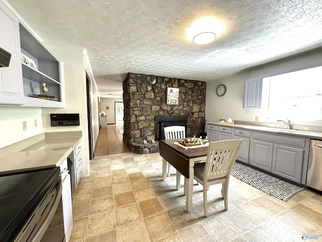kitchen featuring a sink, gray cabinets, plenty of natural light, and a stone fireplace