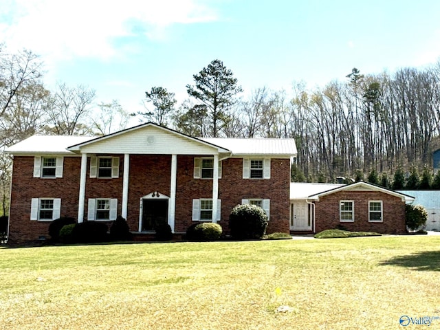 neoclassical home featuring brick siding and a front yard