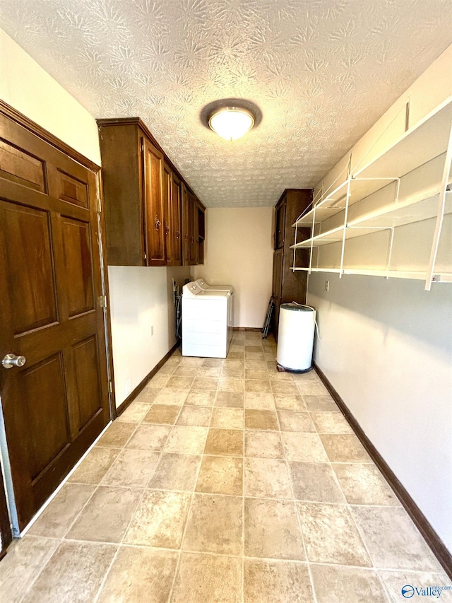 clothes washing area with washer / clothes dryer, baseboards, and a textured ceiling