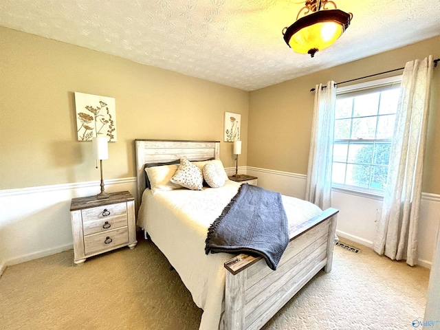 carpeted bedroom featuring visible vents, baseboards, and a textured ceiling