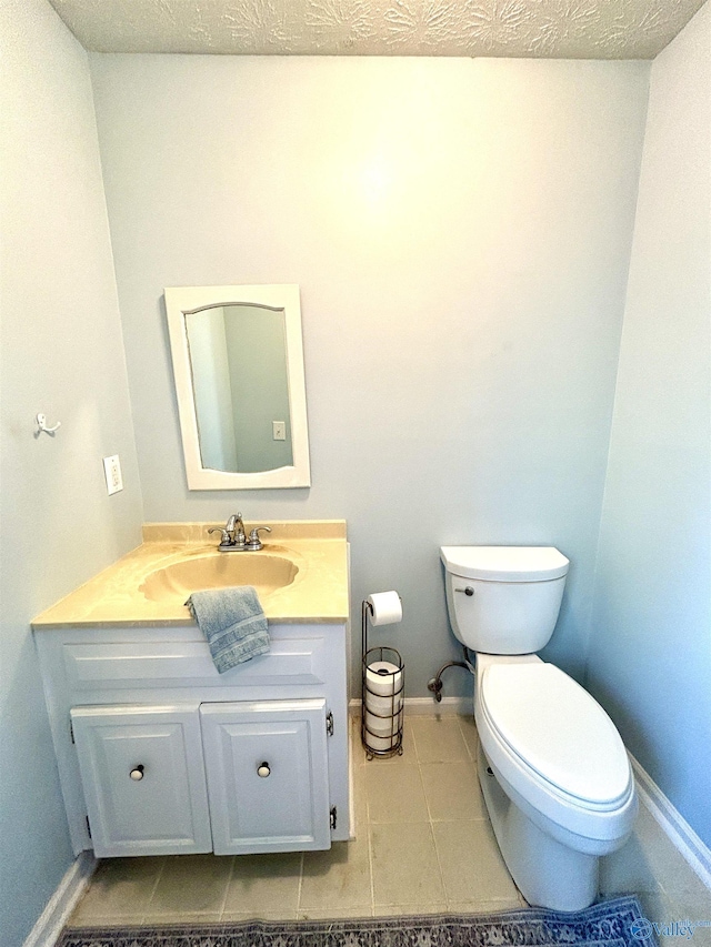 half bath featuring toilet, vanity, tile patterned floors, and baseboards