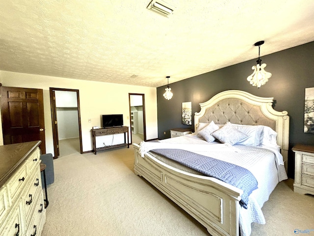 bedroom featuring light colored carpet, visible vents, an inviting chandelier, and a textured ceiling