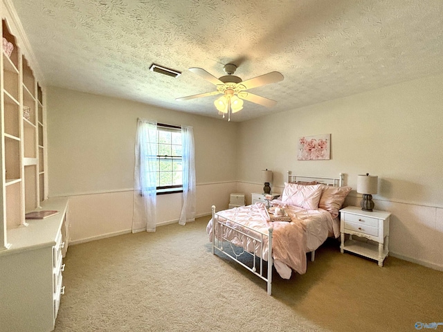 carpeted bedroom with a ceiling fan, a textured ceiling, baseboards, and visible vents