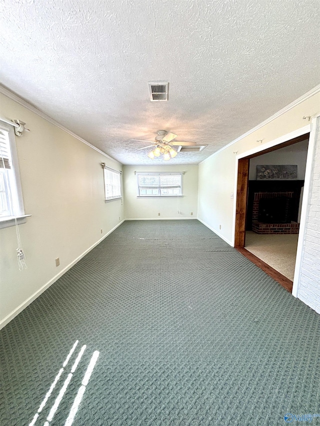 interior space featuring carpet flooring, visible vents, crown molding, a fireplace, and a ceiling fan