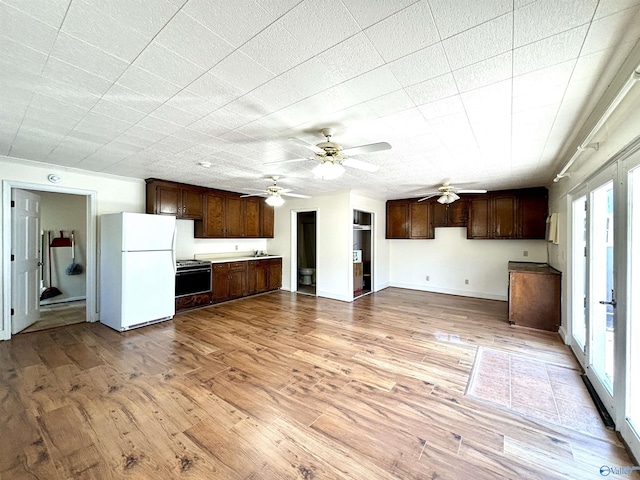 kitchen with freestanding refrigerator, light wood-type flooring, dark brown cabinetry, and range with gas cooktop