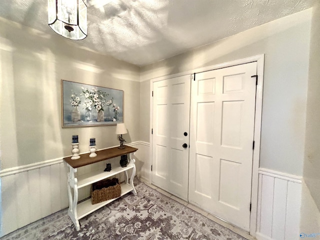 foyer entrance with a wainscoted wall and a textured ceiling