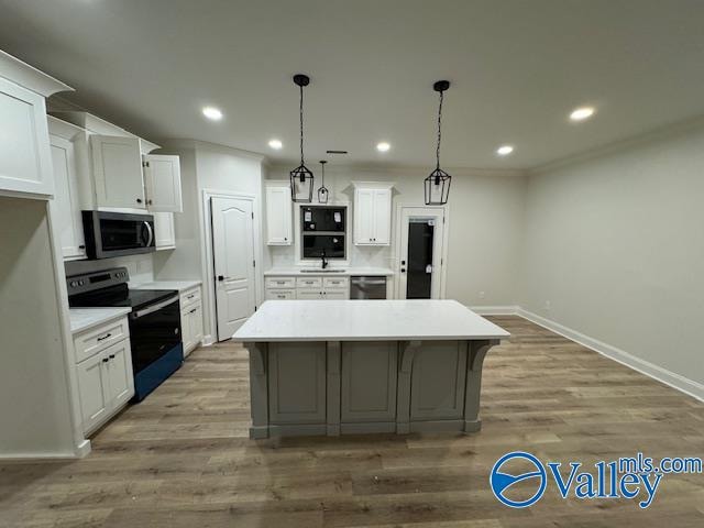 kitchen featuring pendant lighting, a center island, stainless steel appliances, and white cabinetry