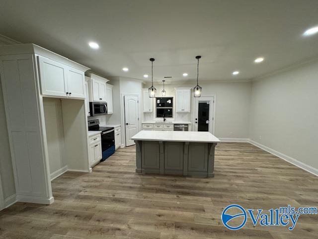 kitchen featuring stainless steel appliances, wood-type flooring, pendant lighting, white cabinets, and a center island