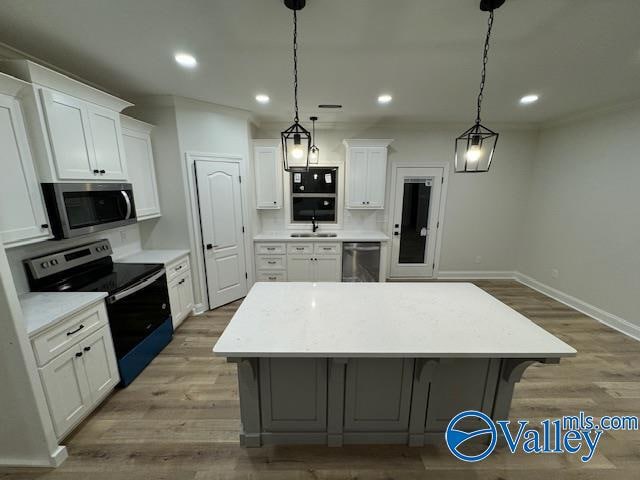 kitchen featuring a center island, white cabinets, sink, appliances with stainless steel finishes, and light hardwood / wood-style floors