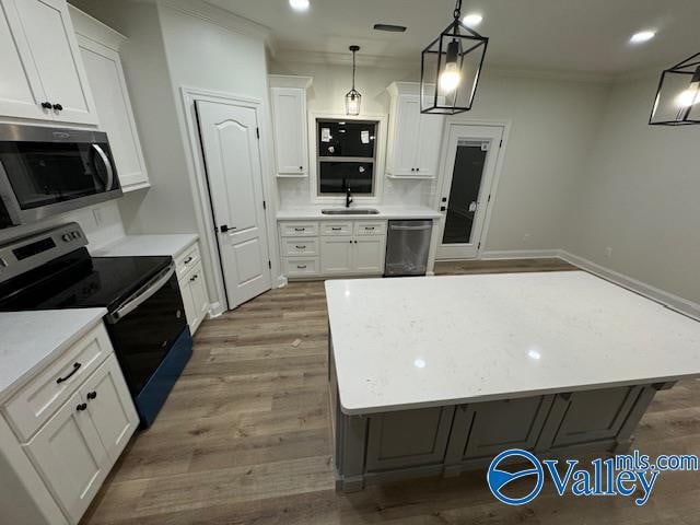 kitchen with hardwood / wood-style flooring, white cabinets, hanging light fixtures, and appliances with stainless steel finishes