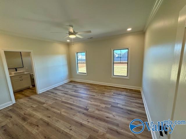 unfurnished bedroom featuring ceiling fan, light hardwood / wood-style flooring, ensuite bathroom, and ornamental molding