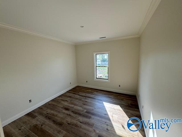 empty room with dark hardwood / wood-style flooring and crown molding