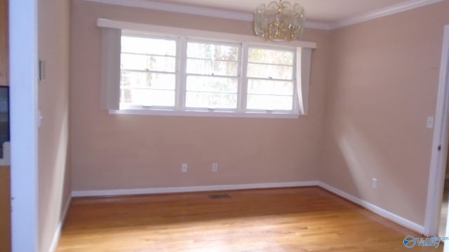 unfurnished room with light hardwood / wood-style flooring, ornamental molding, and a notable chandelier