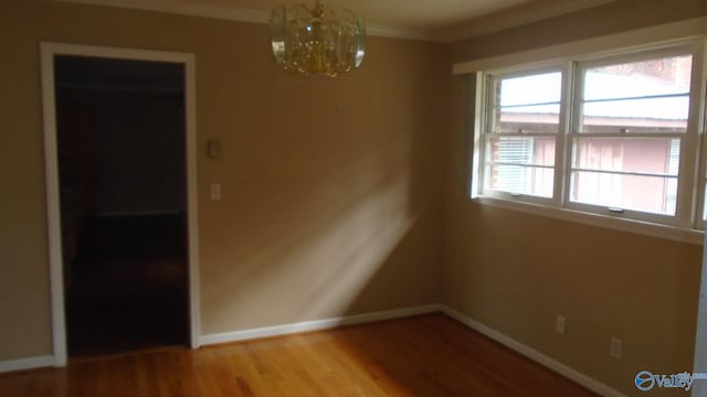 unfurnished room with ornamental molding, light wood-type flooring, and a notable chandelier