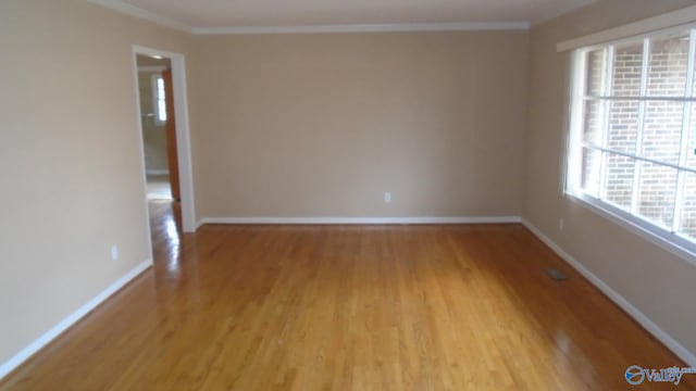 empty room featuring light wood-type flooring and crown molding