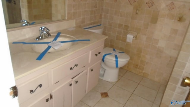 bathroom featuring tile patterned flooring, vanity, toilet, and tile walls