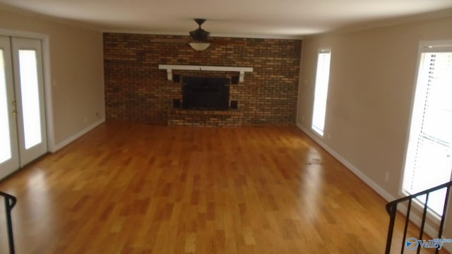 unfurnished living room featuring hardwood / wood-style flooring, brick wall, and a brick fireplace