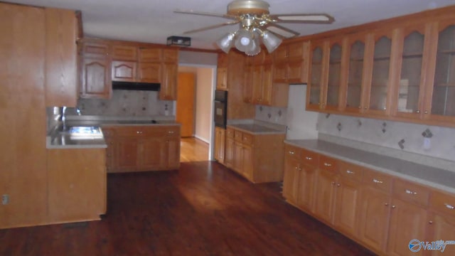 kitchen with ceiling fan, sink, dark wood-type flooring, backsplash, and oven