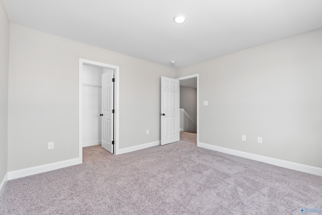 unfurnished bedroom featuring light carpet, a spacious closet, and a closet