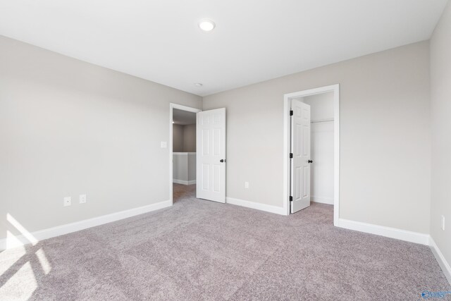 unfurnished bedroom featuring light colored carpet, a spacious closet, and a closet