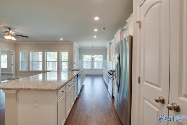 kitchen featuring dark wood-type flooring, gas range oven, ceiling fan with notable chandelier, white cabinetry, and a center island with sink