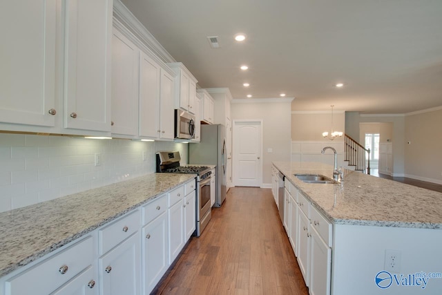 kitchen with hardwood / wood-style flooring, backsplash, appliances with stainless steel finishes, sink, and crown molding