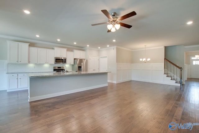 kitchen featuring stainless steel appliances, white cabinetry, decorative light fixtures, and wood-type flooring