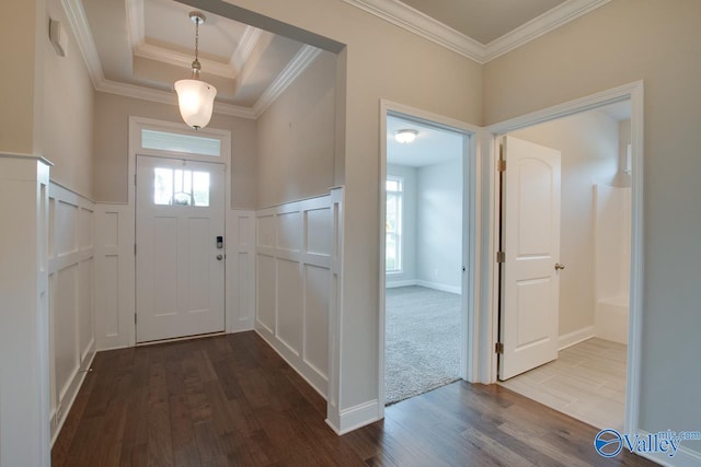 foyer with carpet floors, a raised ceiling, and crown molding