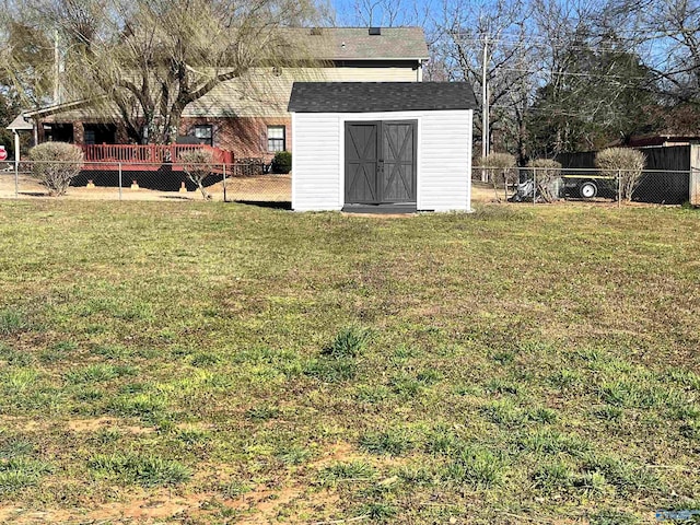 view of yard featuring a deck, a storage unit, an outdoor structure, and fence