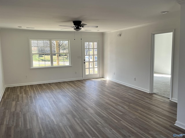 spare room featuring baseboards, plenty of natural light, dark wood finished floors, and crown molding