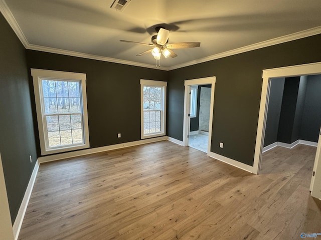 empty room with crown molding, a wealth of natural light, and light wood-type flooring