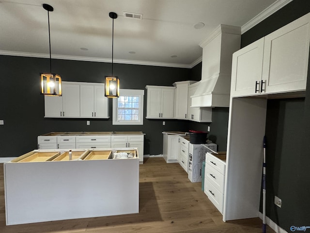 kitchen with white cabinetry, premium range hood, a center island, and hanging light fixtures